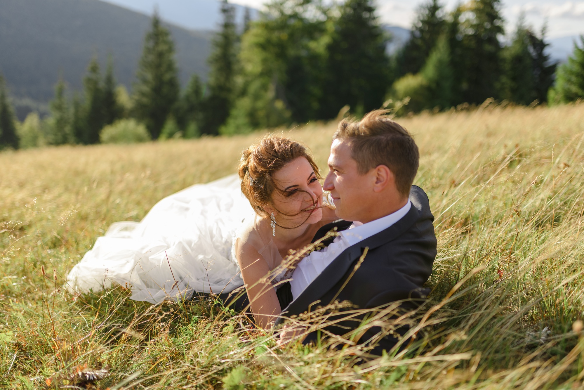 wedding photography in the mountains newlyweds are lying in the grass .jpg